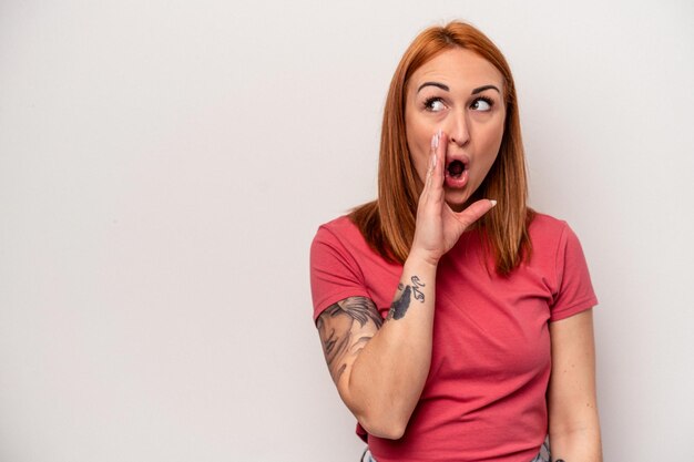 Young caucasian woman isolated on white background is saying a secret hot braking news and looking aside