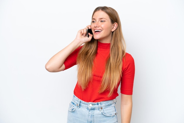 Foto giovane donna caucasica isolata su sfondo bianco mantenendo una conversazione con il telefono cellulare