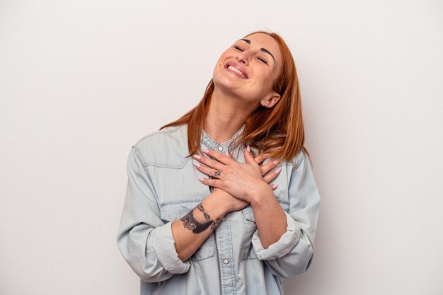 Young caucasian woman isolated on white background laughing keeping hands on heart concept of happiness