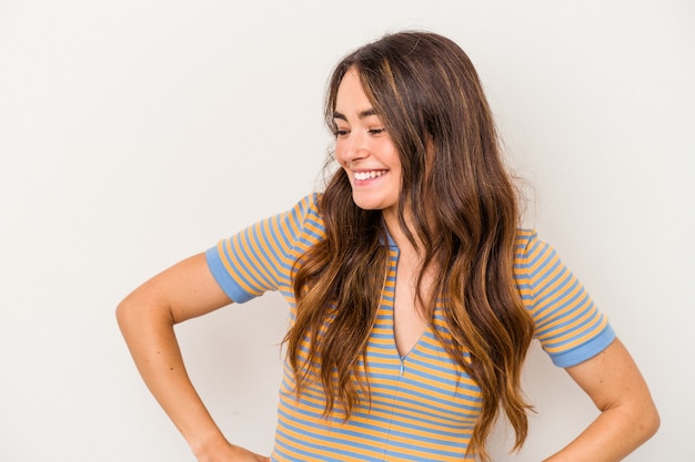 Young caucasian woman isolated on white background laughs happily and has fun keeping hands on stomach.