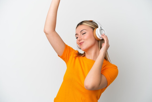 Young caucasian woman isolated on white background listening music and dancing