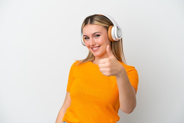 Young caucasian woman isolated on white background listening music and with thumb up