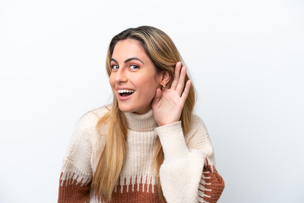 Young caucasian woman isolated on white background listening to something by putting hand on the ear