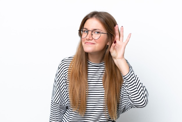 Young caucasian woman isolated on white background listening to something by putting hand on the ear