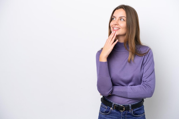 Young caucasian woman isolated on white background looking up while smiling