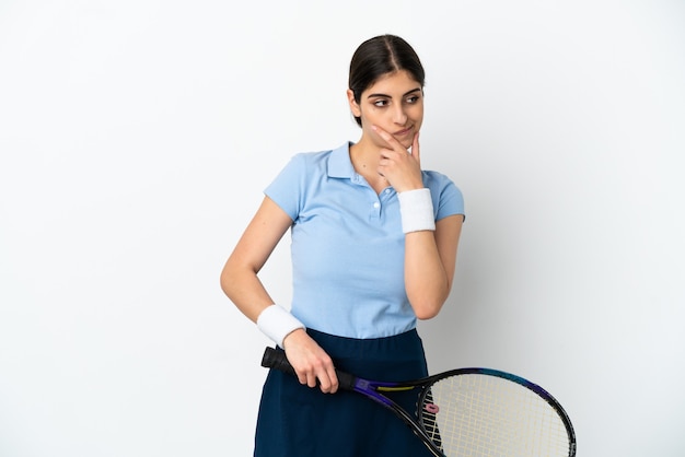 Young caucasian woman isolated on white background playing tennis and thinking