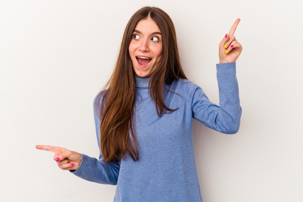 Young caucasian woman isolated on white background pointing to different copy spaces, choosing one of them, showing with finger.