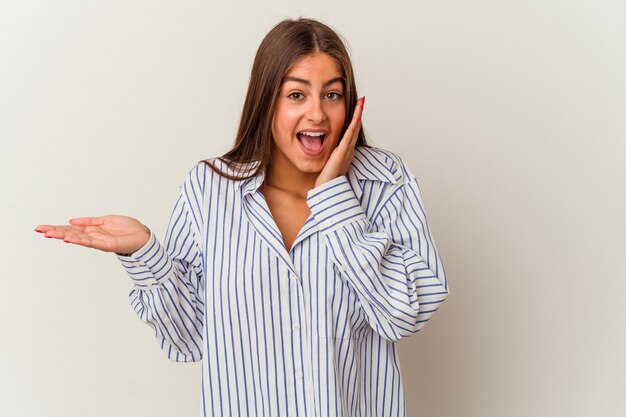 Giovane donna caucasica isolata su sfondo bianco che indica con l'indice uno spazio di copia, esprimendo eccitazione e desiderio.