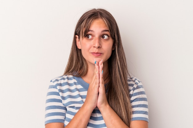 Young caucasian woman isolated on white background praying, showing devotion, religious person looking for divine inspiration.