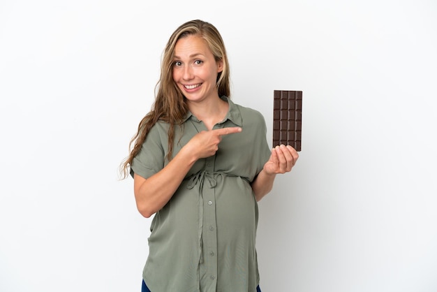 Young caucasian woman isolated on white background pregnant and holding chocolate