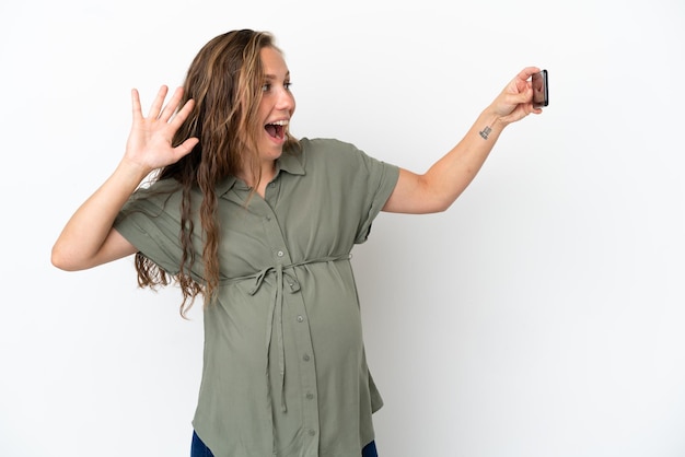 Young caucasian woman isolated on white background pregnant and making a selfie