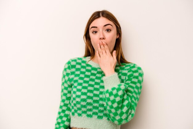 Young caucasian woman isolated on white background shocked covering mouth with hands anxious to discover something new