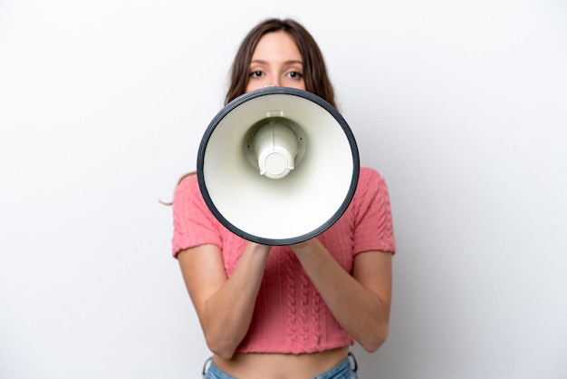 Young caucasian woman isolated on white background shouting through a megaphone to announce something