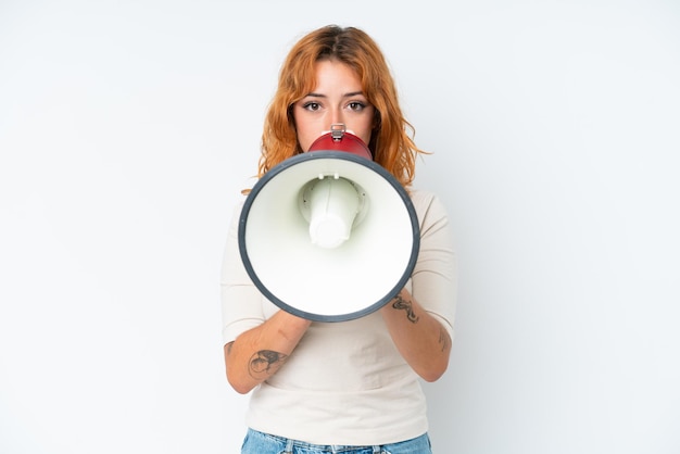 Foto giovane donna caucasica isolata su sfondo bianco che grida tramite un megafono per annunciare qualcosa