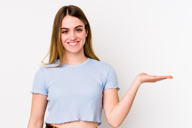 Young caucasian woman isolated on white background showing a copy space on a palm and holding another hand on waist.