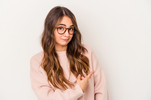 Young caucasian woman isolated on white background smiling and pointing aside, showing something at blank space.