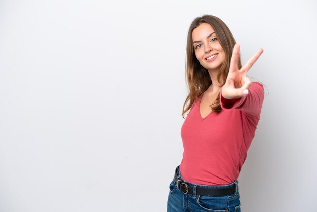 Giovane donna caucasica isolata su fondo bianco che sorride e che mostra il segno di vittoria