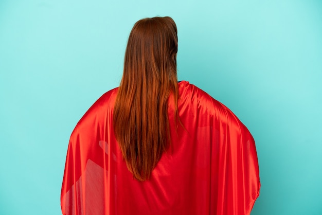 Giovane donna caucasica isolata su sfondo bianco in costume da supereroe in posizione posteriore