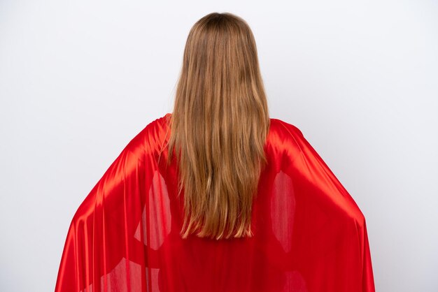 Young caucasian woman isolated on white background in superhero costume in back position