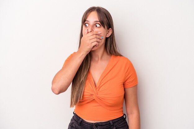 Young caucasian woman isolated on white background thoughtful looking to a copy space covering mouth with hand.