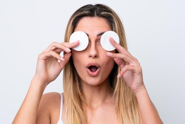 Young caucasian woman isolated on white background with cotton pad for removing makeup from her face