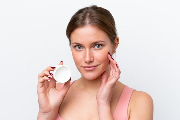 Young caucasian woman isolated on white background with moisturizer