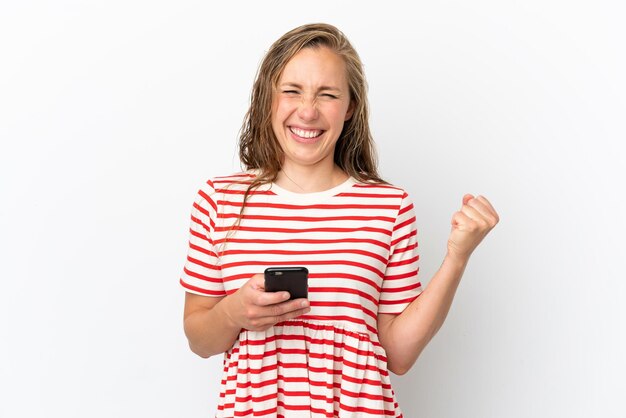 Young caucasian woman isolated on white background with phone in victory position