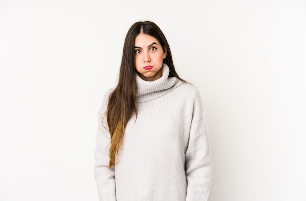 Young caucasian woman isolated on white blows cheeks, has tired expression. Facial expression concept.