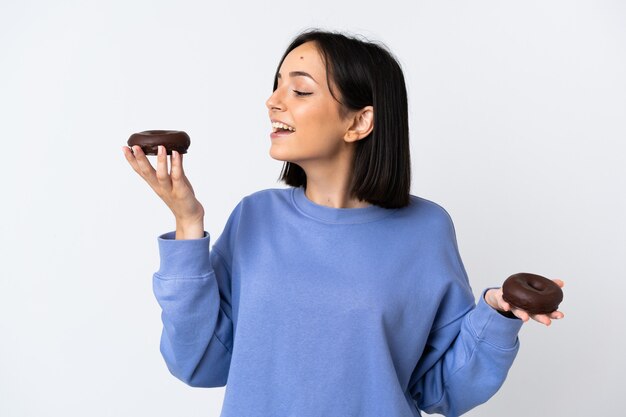 Young caucasian woman isolated on white holding donuts with happy expression