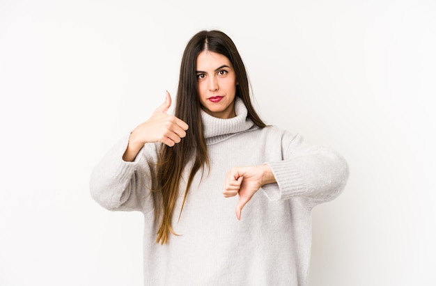 Young caucasian woman isolated on a white showing thumbs up and thumbs down, difficult choose concept