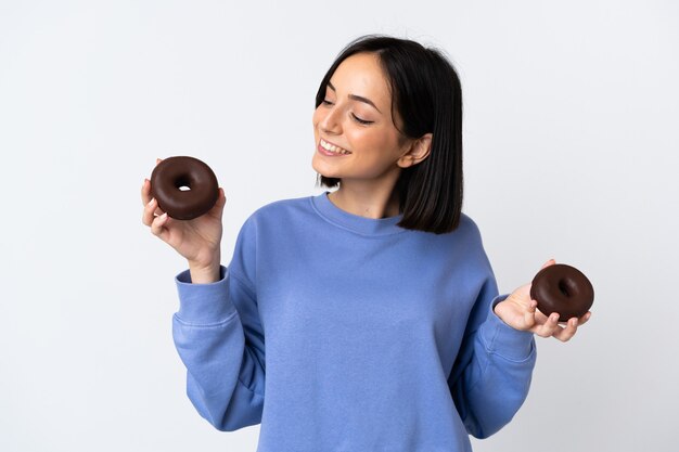 Young caucasian woman isolated on white wall holding donuts with happy expression