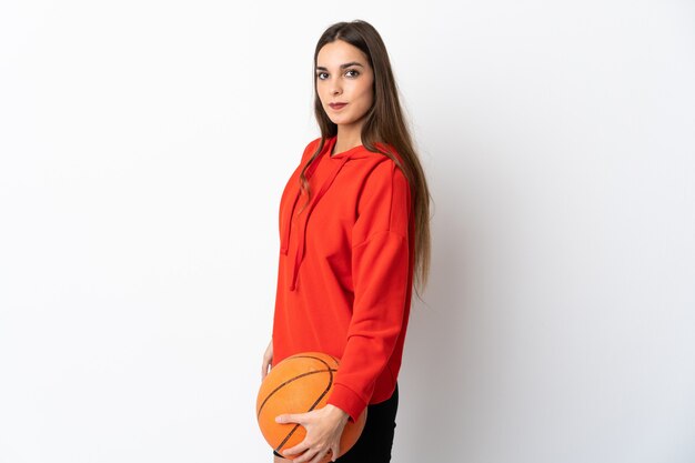 Young caucasian woman isolated on white wall playing basketball