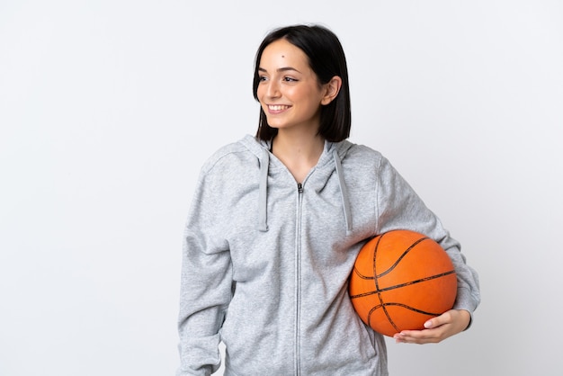 Young caucasian woman isolated on white wall playing basketball