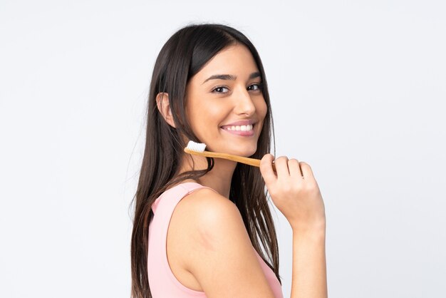 Young caucasian woman isolated on white wall with a toothbrush and happy expression