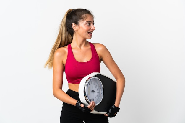 Young caucasian woman isolated on white with weighing machine