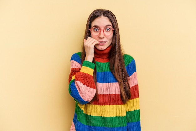 Young caucasian woman isolated on yellow background biting fingernails nervous and very anxious