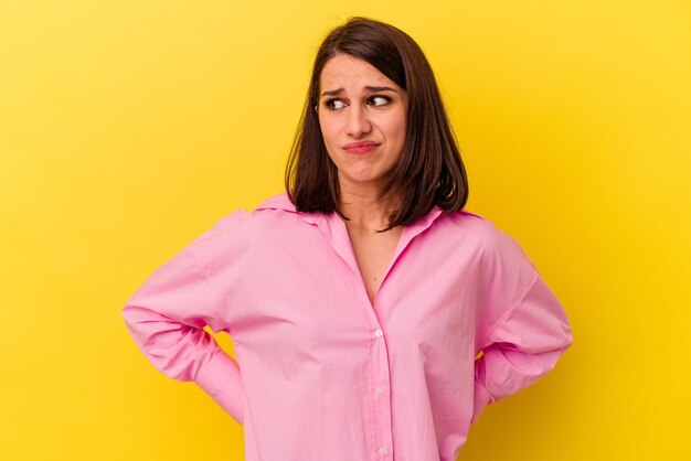 Young caucasian woman isolated on yellow background confused feels doubtful and unsure