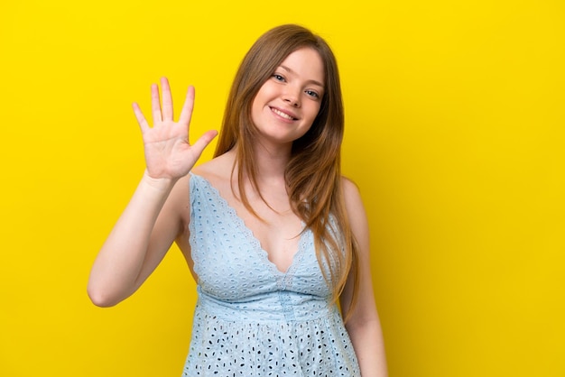 指で5を数える黄色の背景に分離された若い白人女性