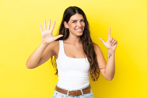 Young caucasian woman isolated on yellow background counting seven with fingers