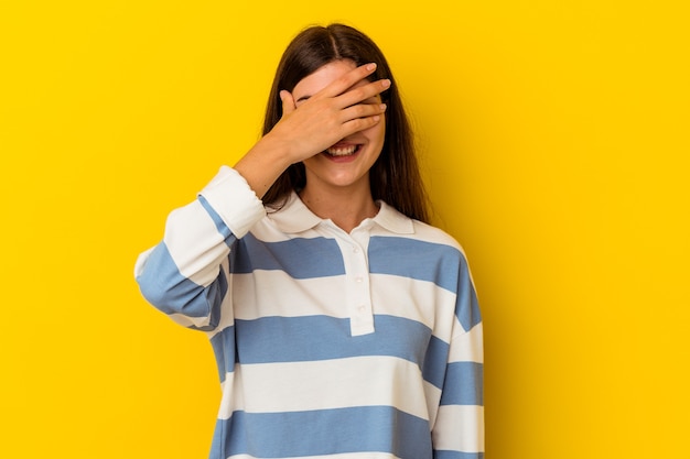 Photo young caucasian woman isolated on yellow background covers eyes with hands, smiles broadly waiting for a surprise.