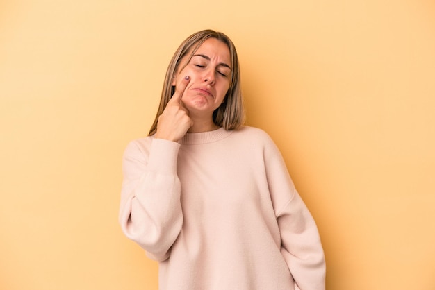 Young caucasian woman isolated on yellow background crying, unhappy with something, agony and confusion concept.