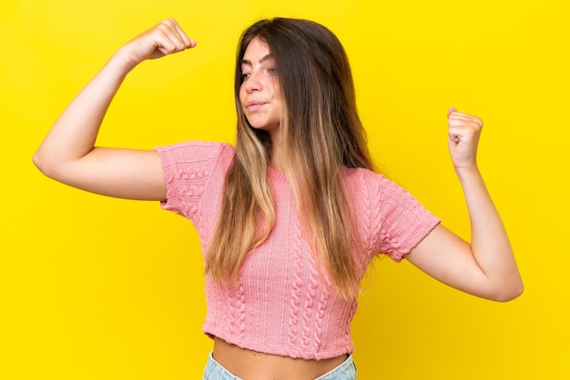 Young caucasian woman isolated on yellow background doing strong gesture