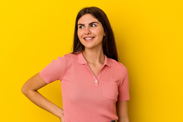 Young caucasian woman isolated on yellow background dreaming of achieving goals and purposes