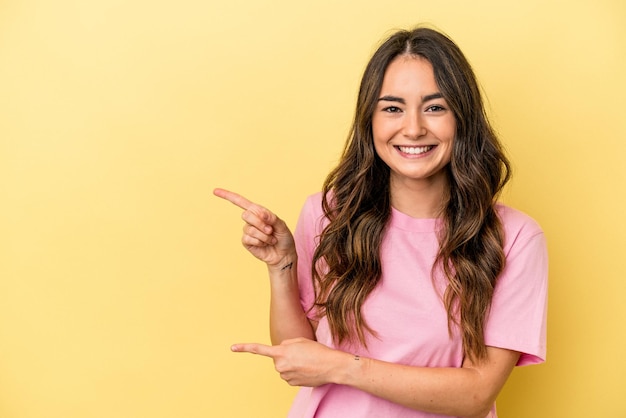 Young caucasian woman isolated on yellow background excited pointing with forefingers away