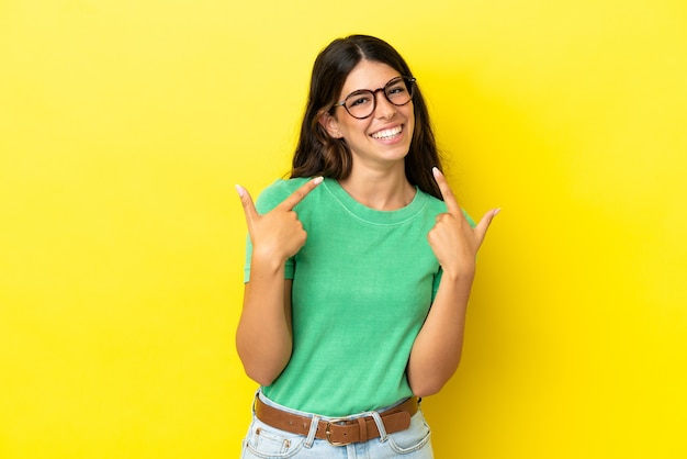 Young caucasian woman isolated on yellow background giving a thumbs up gesture