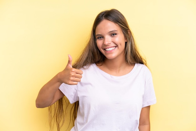 Young caucasian woman isolated on yellow background giving a thumbs up gesture