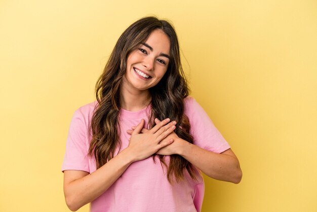 Young caucasian woman isolated on yellow background has friendly expression pressing palm to chest Love concept