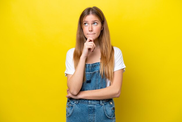 Young caucasian woman isolated on yellow background having doubts and thinking