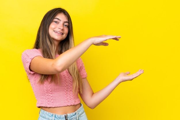 Young caucasian woman isolated on yellow background holding copyspace to insert an ad