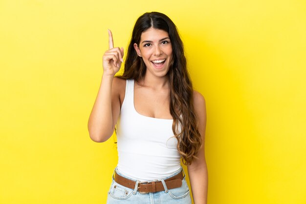 Young caucasian woman isolated on yellow background intending to realizes the solution while lifting a finger up